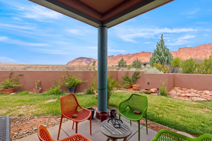 Covered patio with a concrete slab, expansive lawn, and natural rock landscaping
