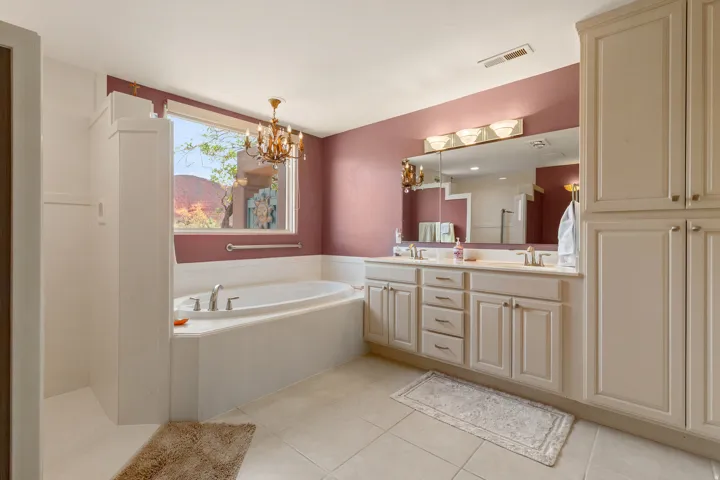 Built-in soaking tub, dual vanity with undermount sinks, ample storage cabinetry, and a window with mountain scenery