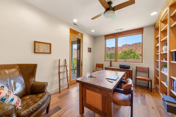 Wood-finish flooring, built-in shelving, ceiling fan, recessed lighting, and a prominent window