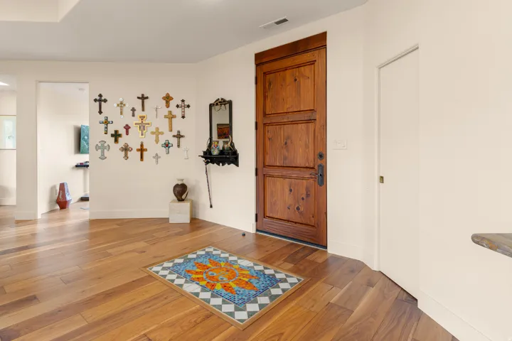 Solid wood entry door with dark hardware, wood-finish flooring, and light-toned walls