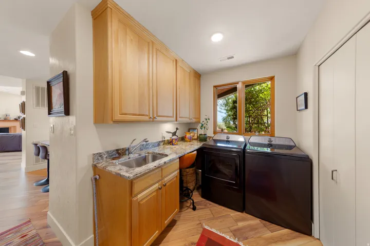 Upper and lower wood cabinetry, granite-style countertop, stainless steel sink, and wood-finish flooring
