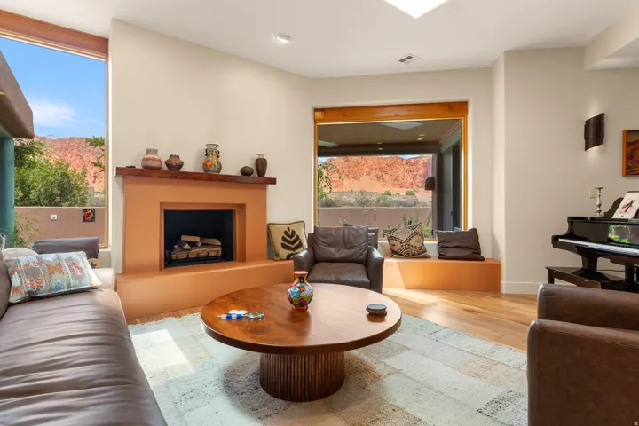 Living area featuring a floor-to-ceiling window, a built-in fireplace, a built-in window bench, hardwood flooring, and a skylight
