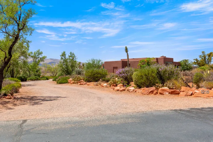 Terracotta stucco exterior with a flat roofline, surrounded by desert landscaping and mature trees