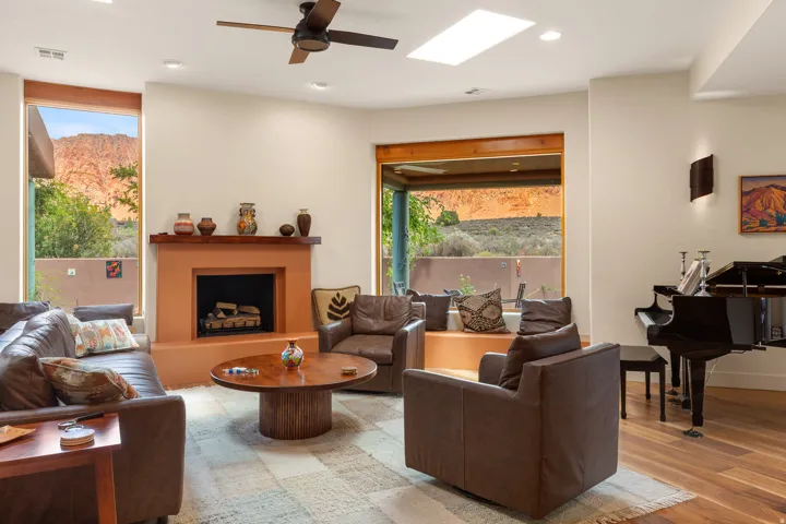 Living space featuring a central fireplace with wood mantel, a skylight, wood-finish flooring, and large windows