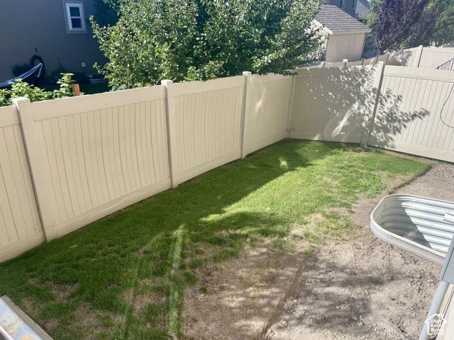 Enclosed yard featuring perimeter fencing and a grass lawn