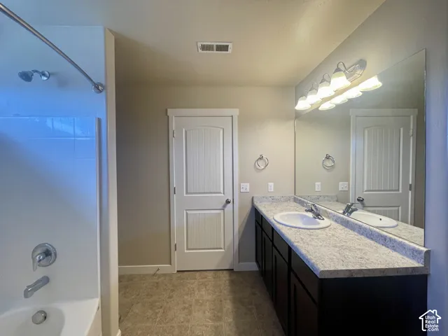 Double vanity with two undermount sinks, speckled countertop, and dark wood-finish cabinetry