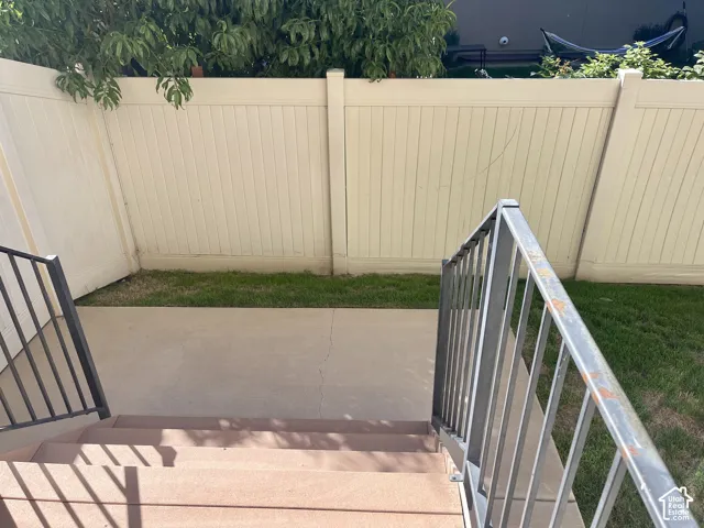 Patio area featuring concrete surface, partial grass strip, and durable privacy fencing
