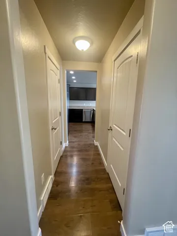 Hallway with wood-finish flooring, white paneled doors, and a flush mount ceiling light