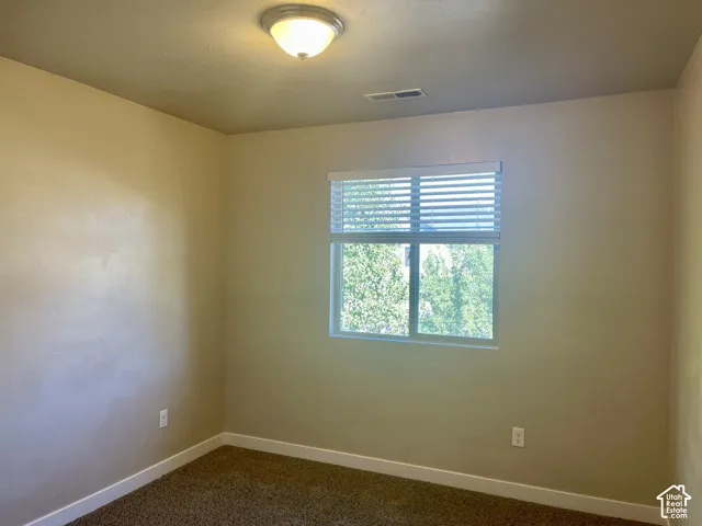 Neutral-toned walls, recessed window with blinds, overhead flush mount light, and carpet flooring