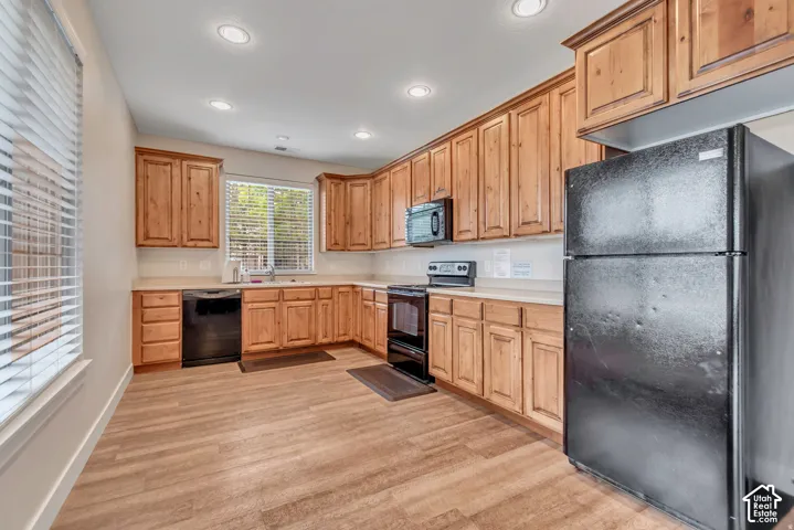 Kitchen featuring wood-finish flooring, wood cabinetry, recessed lighting, and a window with blinds
