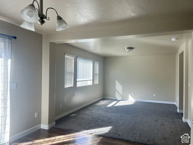 Open-concept room featuring wood-finish flooring, neutral wall paint, and multiple windows with blinds