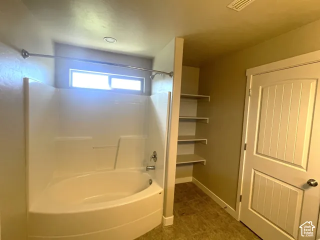 Built-in corner tub with shower, chrome fixtures, and transom window
