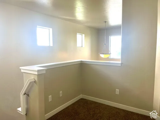Loft area with abundant natural light, recessed windows, textured walls, and a decorative pendant light fixture