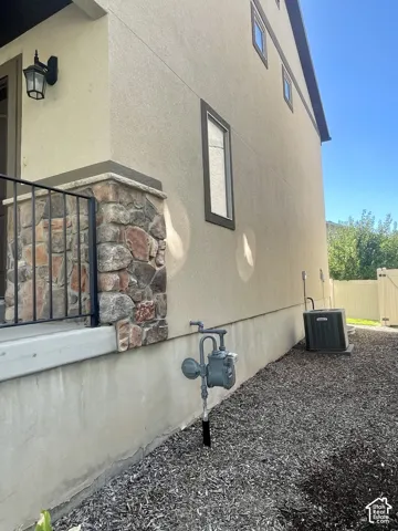 Stucco exterior with stone accent column, dark-framed windows, and exterior light fixture