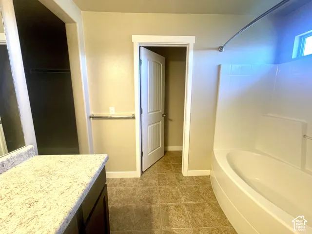Built-in bathtub with integrated seating, tiled floor, and a vanity with a light-colored countertop
