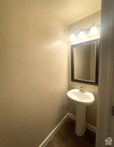 Pedestal sink with chrome faucet, framed mirror, and three-light vanity fixture