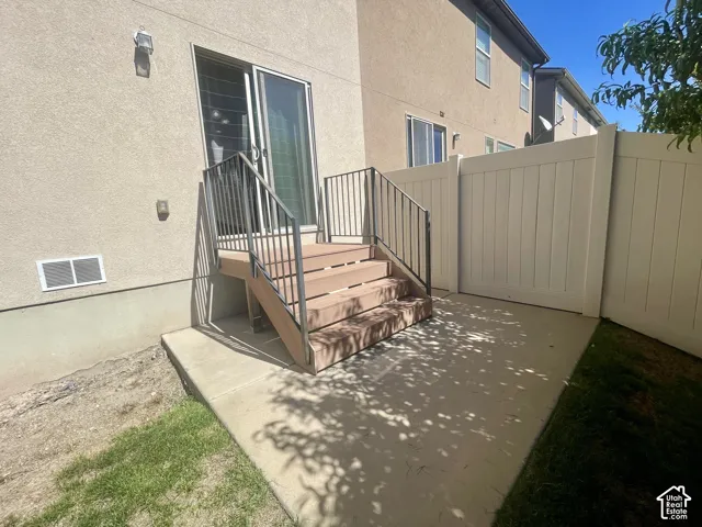 Concrete patio with a composite deck, metal railings, and privacy fencing