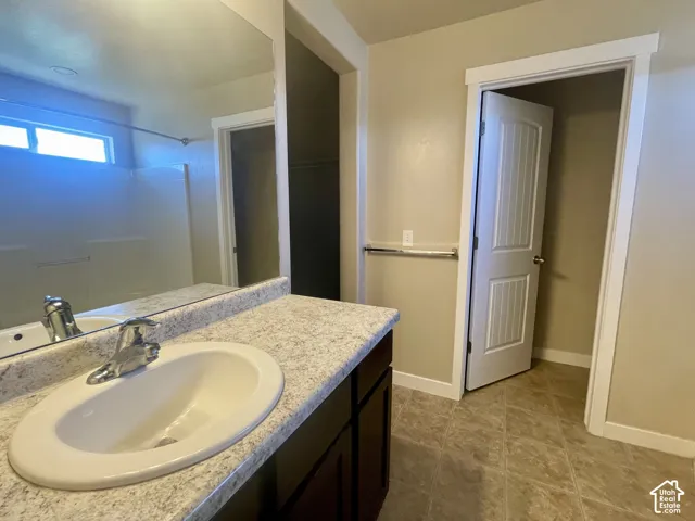 Bathroom featuring a vanity with an integrated sink, polished chrome faucet, and a large wall-mounted mirror