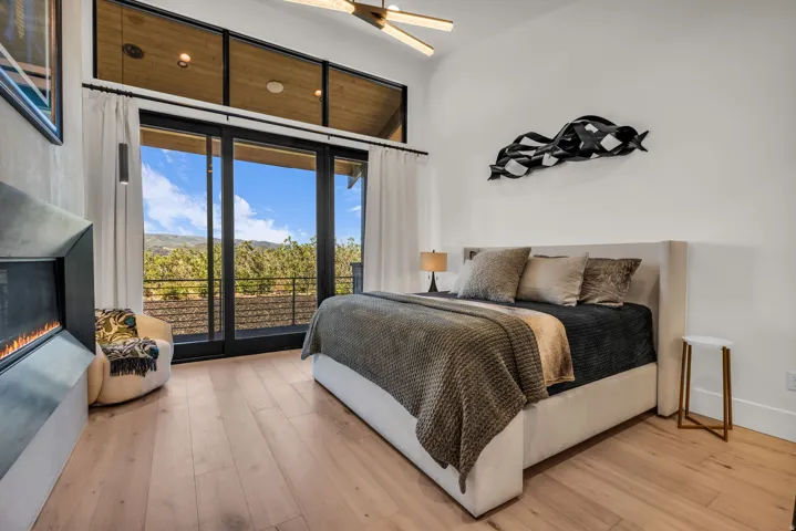 Vaulted ceiling with wood-finish accents, expansive sliding glass doors, light wood-finish flooring, and a built-in fireplace