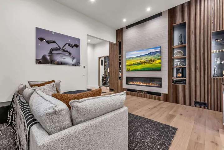Hardwood flooring, recessed lighting, built-in display shelving, and a wall-mounted electric fireplace with a media center