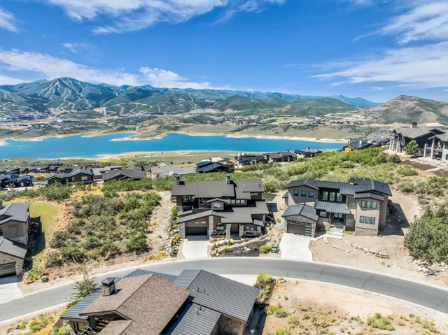 Modern-style residences featuring dark-toned siding and multiple windows, situated on a hillside with paved driveways
