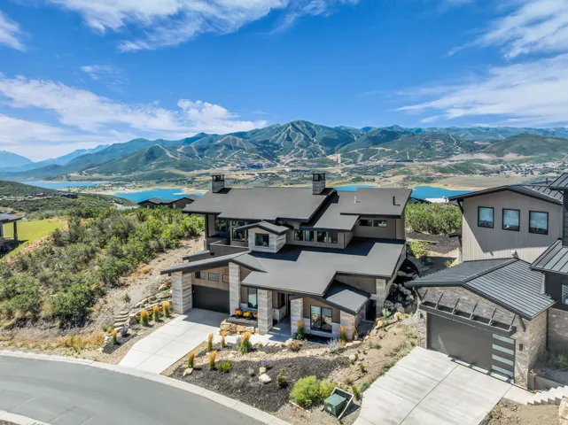 Contemporary architectural style with a multi-level design, stone and wood-look exterior finishes, and an attached garage