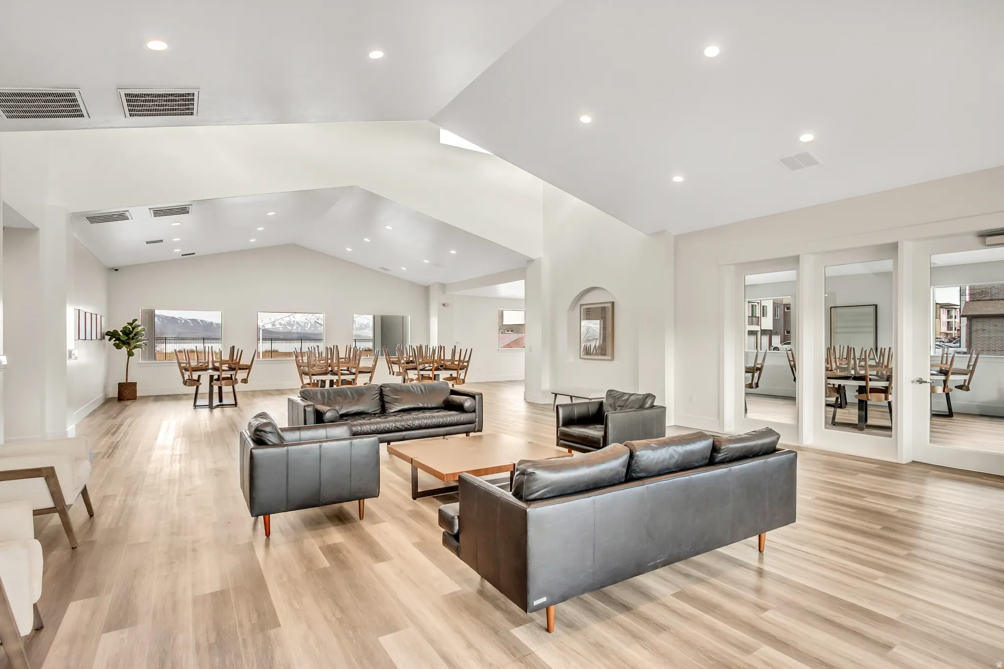 Spacious communal area featuring vaulted ceilings, recessed lighting, wood-finish flooring, and multiple window exposures
