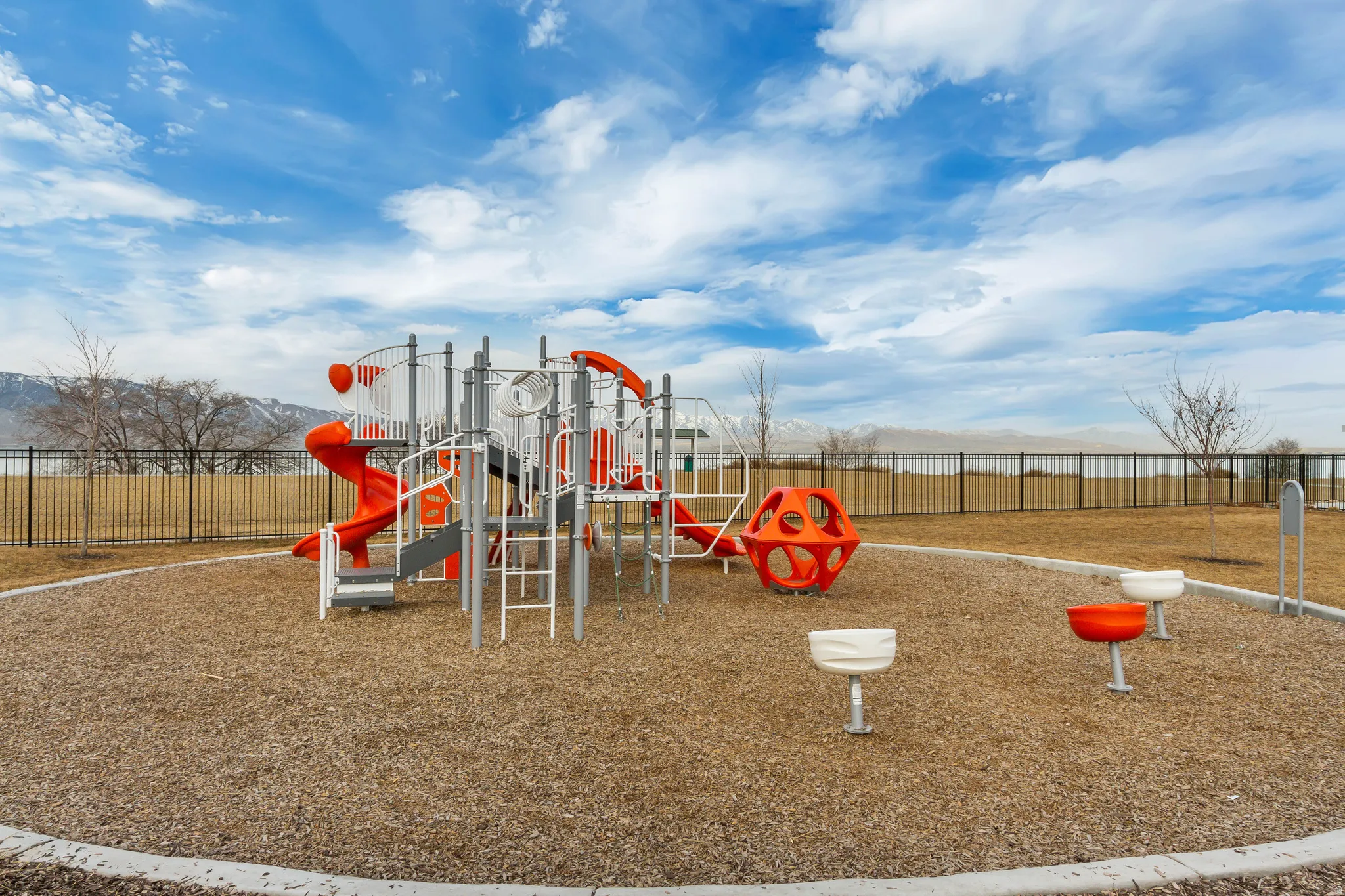 Outdoor playground featuring multiple slides, climbing structures, and ground-level play elements