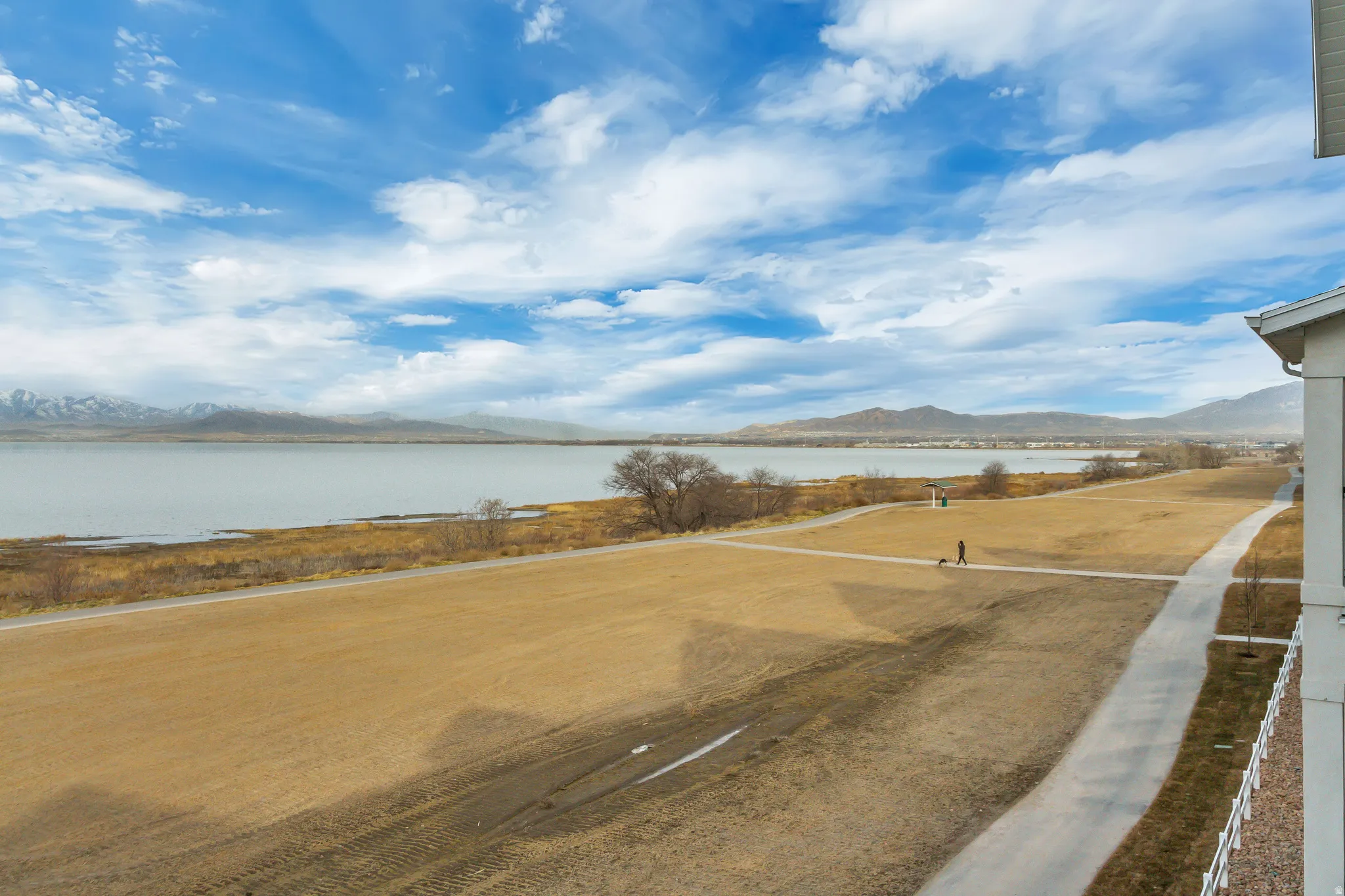 Expansive water body, distant mountains, and paved walking path