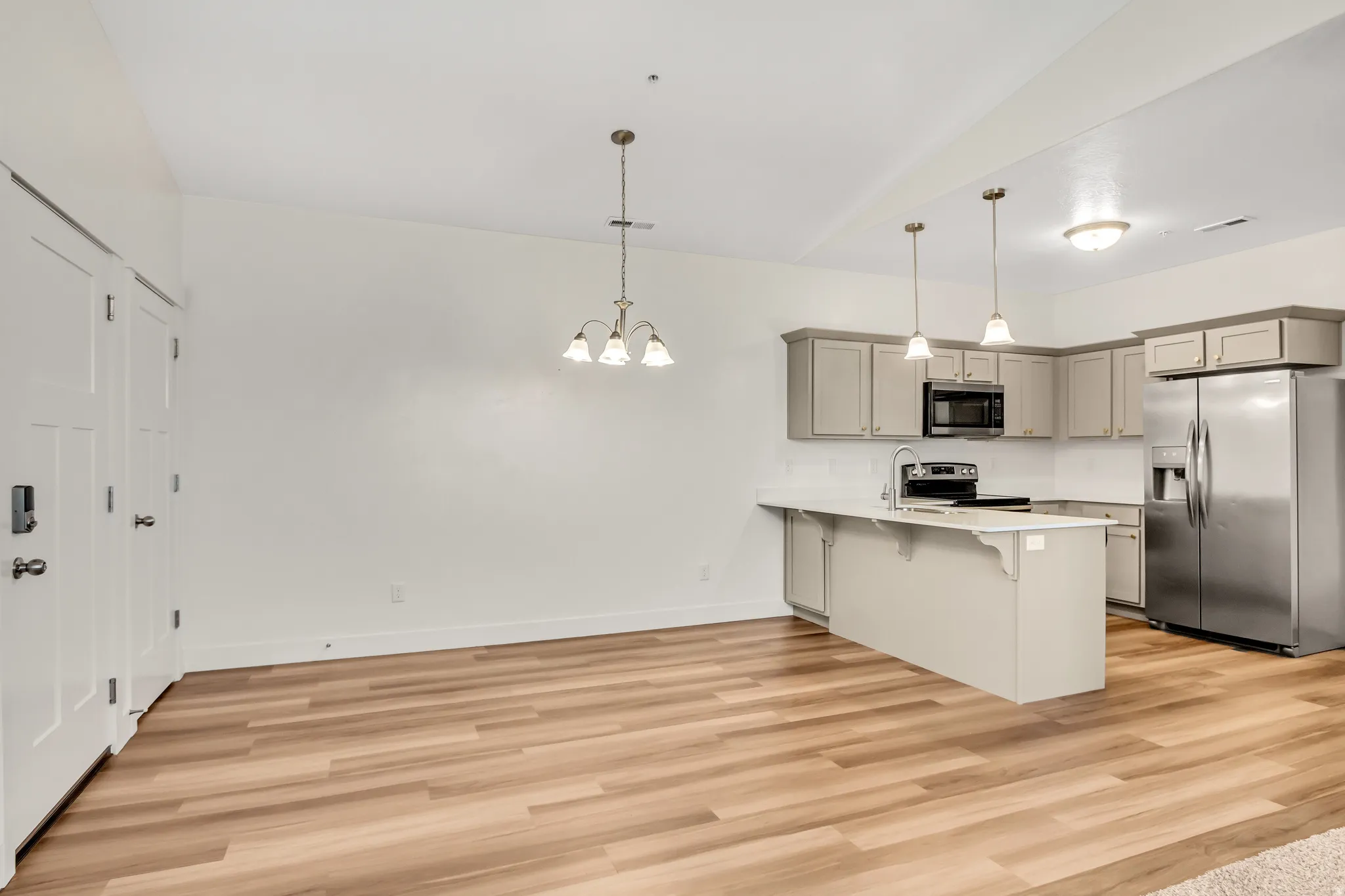 Kitchen featuring wood-finish flooring, white countertops, stainless steel appliances, and grey cabinetry with pendant lighting