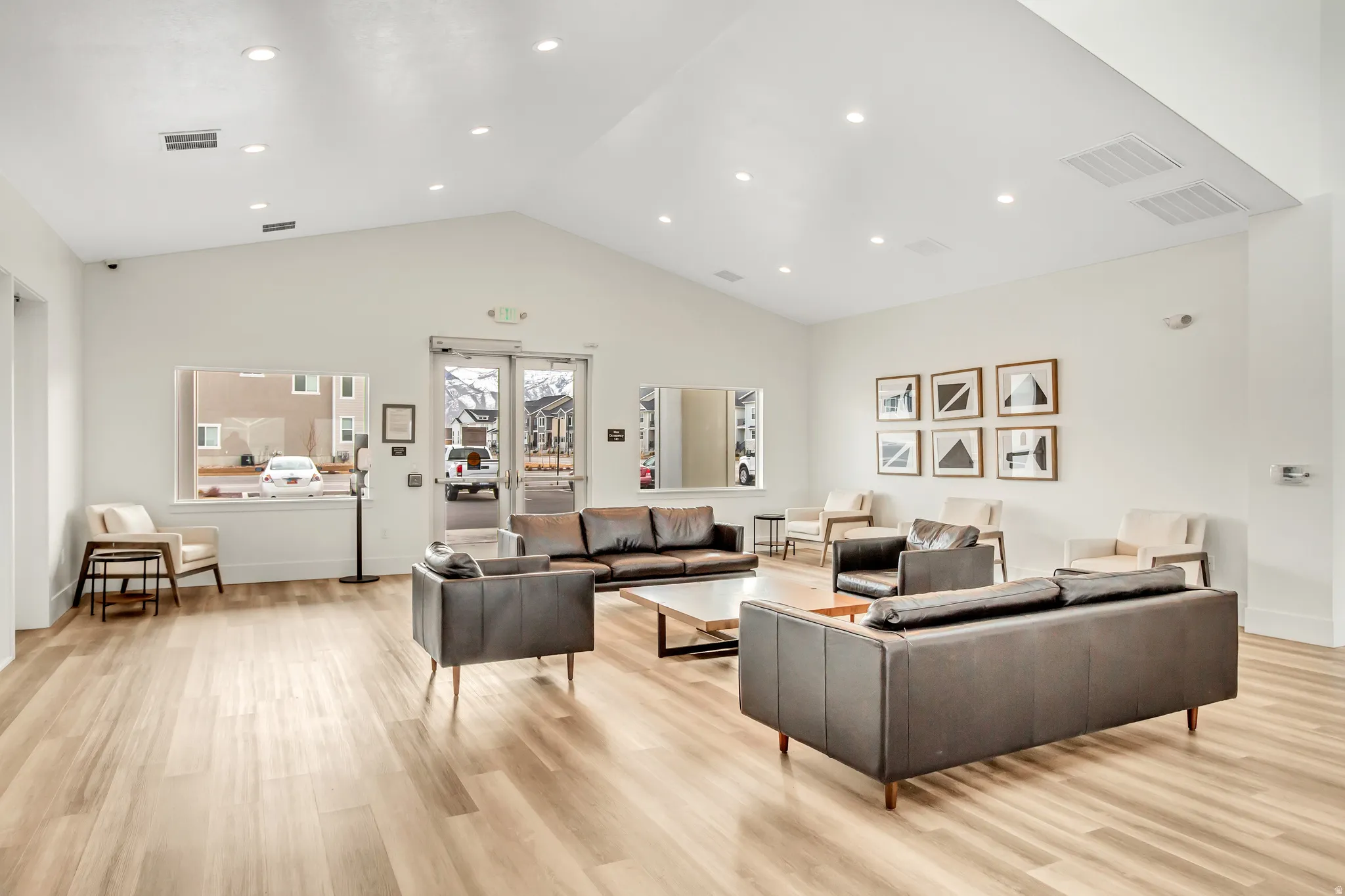 Vaulted ceiling with recessed lighting, wood-finish flooring, large windows, and a glass-paneled entry door
