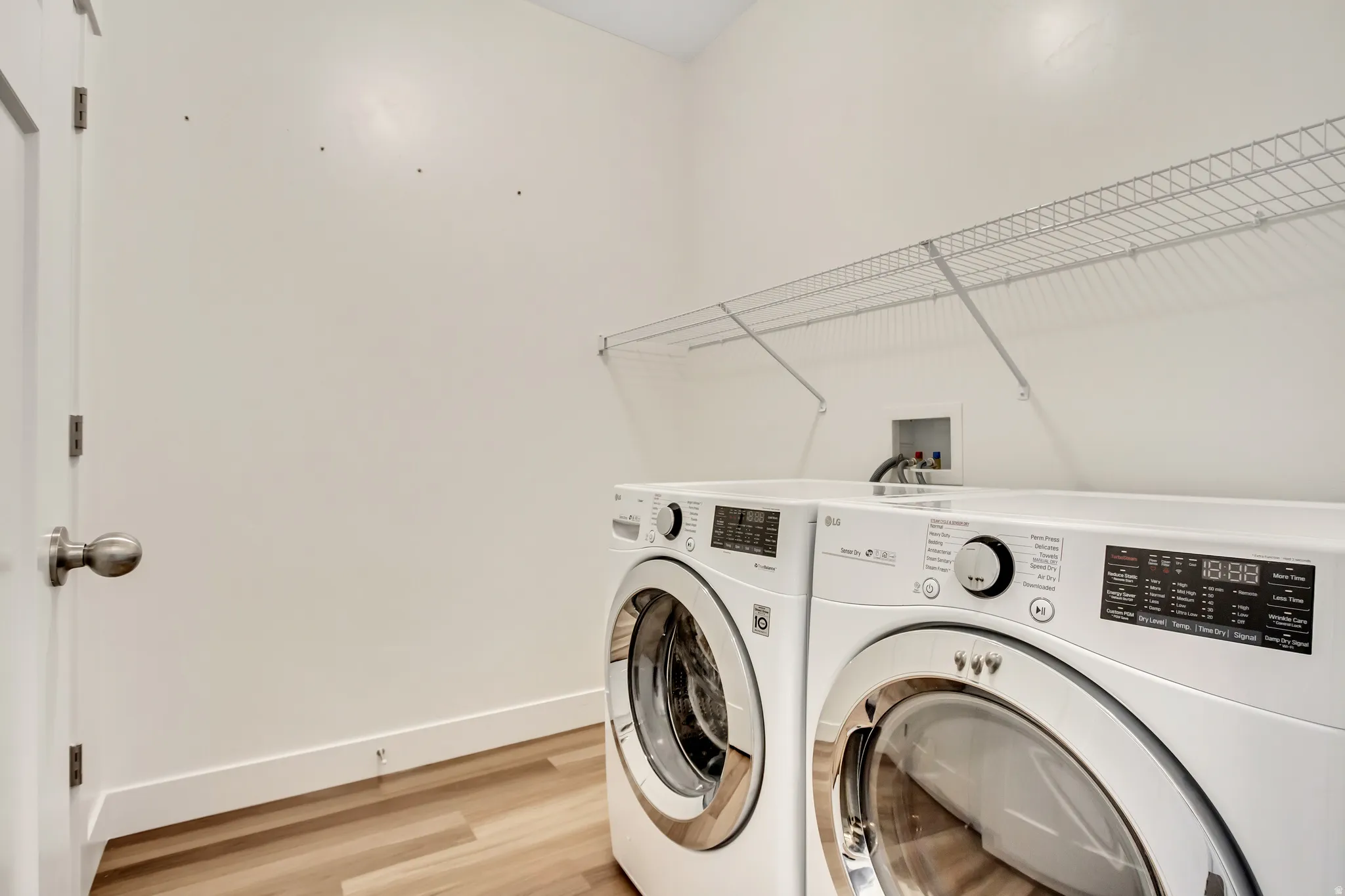Laundry area featuring wood-finish flooring and a white wire shelf
