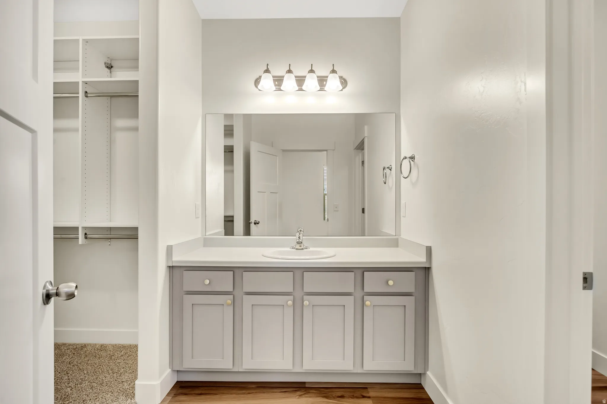 Built-in vanity with a single basin sink, light gray cabinetry, and a rectangular mirror