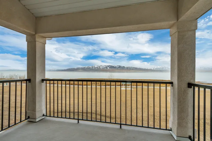 Covered balcony with black metal railings, offering a scenic water and mountain backdrop