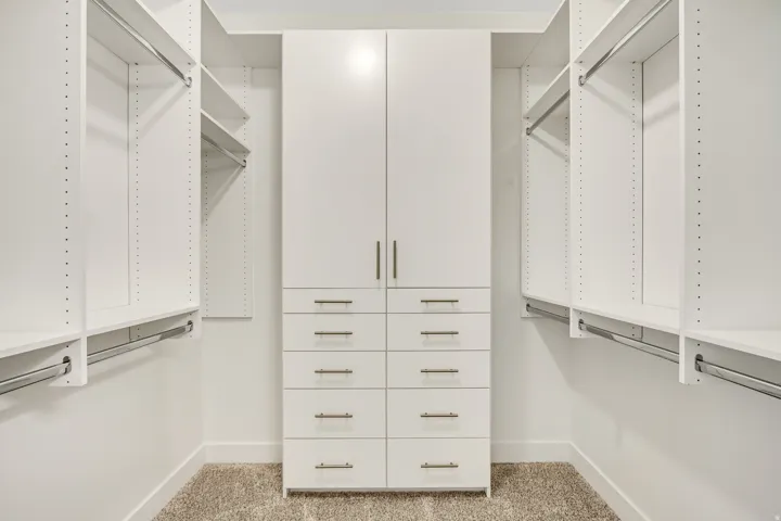 Custom closet system with integrated shelving, hanging rods, and central drawer storage