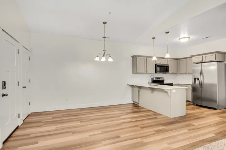 Kitchen featuring wood-finish flooring, white countertops, stainless steel appliances, and grey cabinetry with pendant lighting