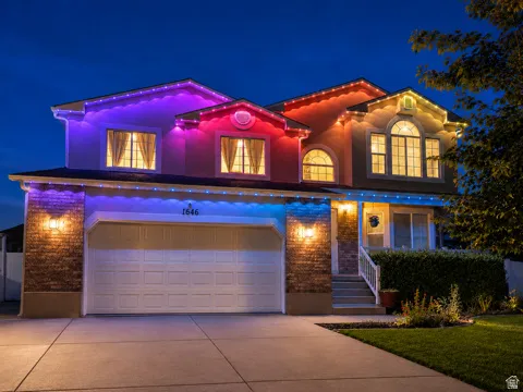 Stucco exterior with brick accents, arched and rectangular windows, a two-car garage, and a concrete driveway