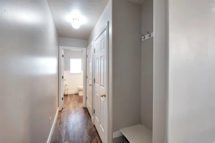 Hallway with wood-finish flooring, recessed lighting, white panel doors, and a built-in coat rack with bench
