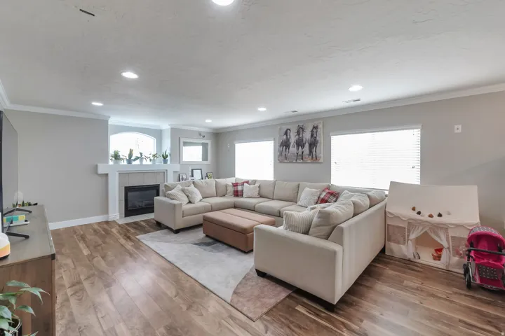 Spacious living area featuring wood-finish flooring, recessed lighting, and a fireplace with a tiled surround
