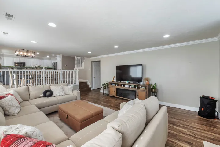 Wood-finish flooring, recessed lighting, crown molding, and a white baluster railing