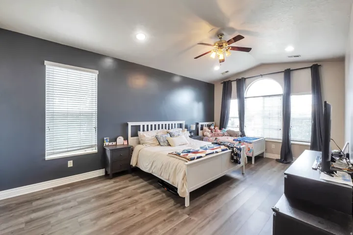 Wood-finish flooring, vaulted ceiling, arched window, recessed lighting, and a ceiling fan