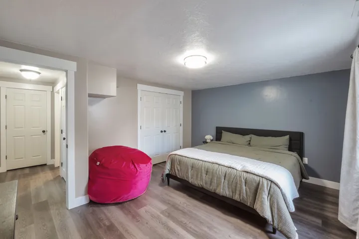 Wood-finish flooring throughout, a two-door closet with black hardware, and a bedroom featuring an accent wall