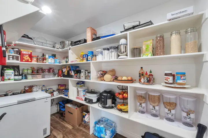 Spacious pantry featuring extensive built-in shelving, wood-finish flooring, and recessed ceiling lighting