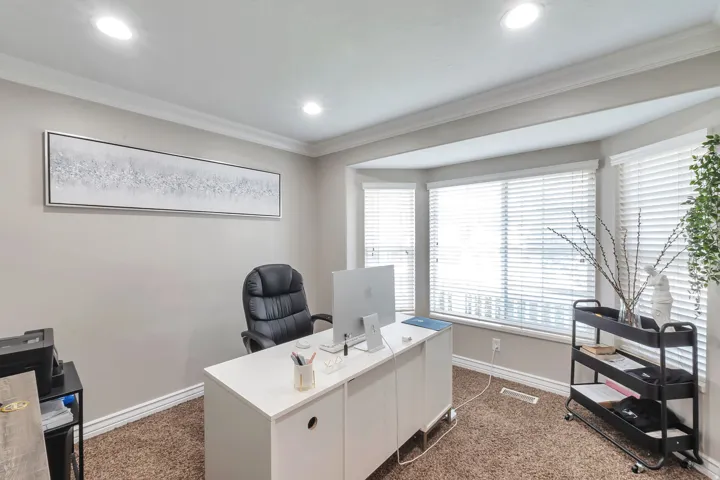 Recessed lighting illuminating the room, crown molding detailing, and a bay window with blinds