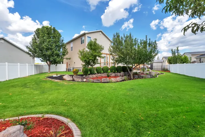 Expansive lawn with mature trees and a decorative rock garden