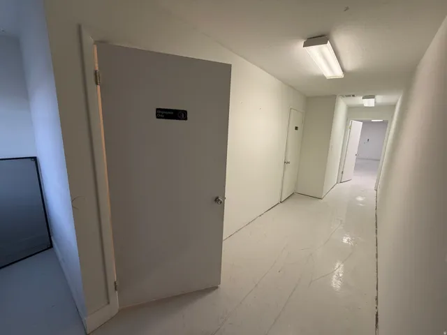 Hallway with painted concrete flooring and overhead fluorescent lighting