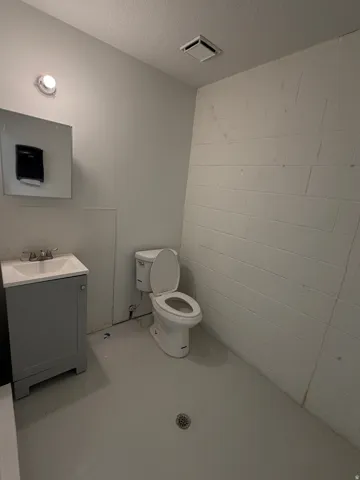 White toilet, single vanity with integrated sink, and overhead lighting