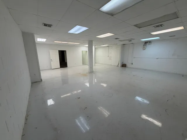 Spacious open-concept interior featuring a drop ceiling with integrated lighting, painted concrete flooring, and exposed block walls