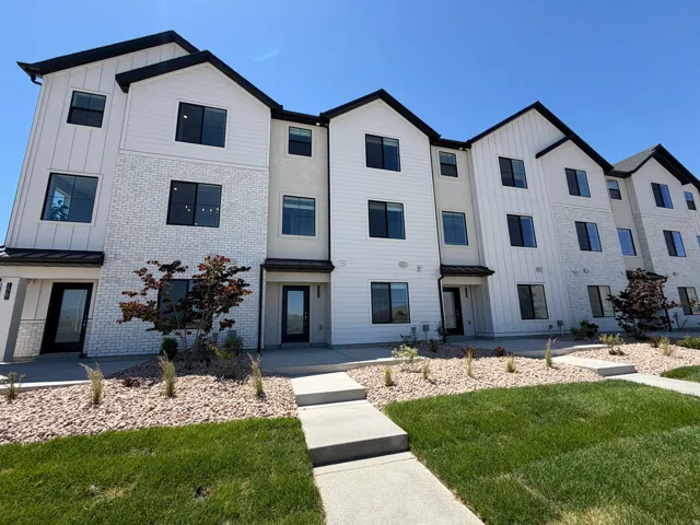 Modern multi-story facade featuring white board and batten siding, textured white brick, and dark framed windows