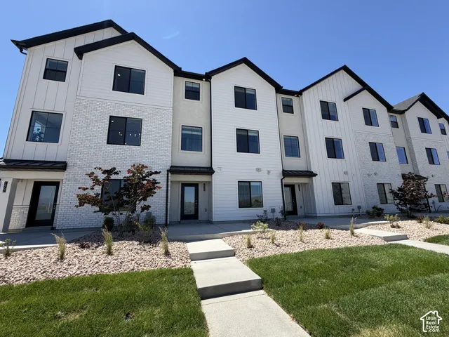 Modern multi-story facade featuring white board and batten siding, textured white brick, and dark framed windows
